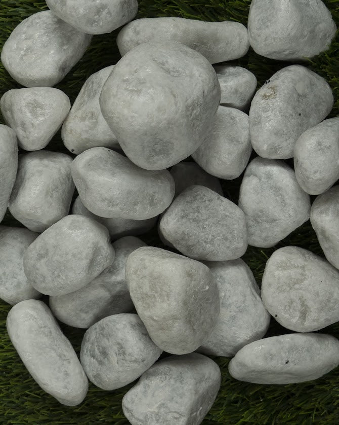 Gruppo di ciottoli di marmo bianco di Carrara su manto d'erba